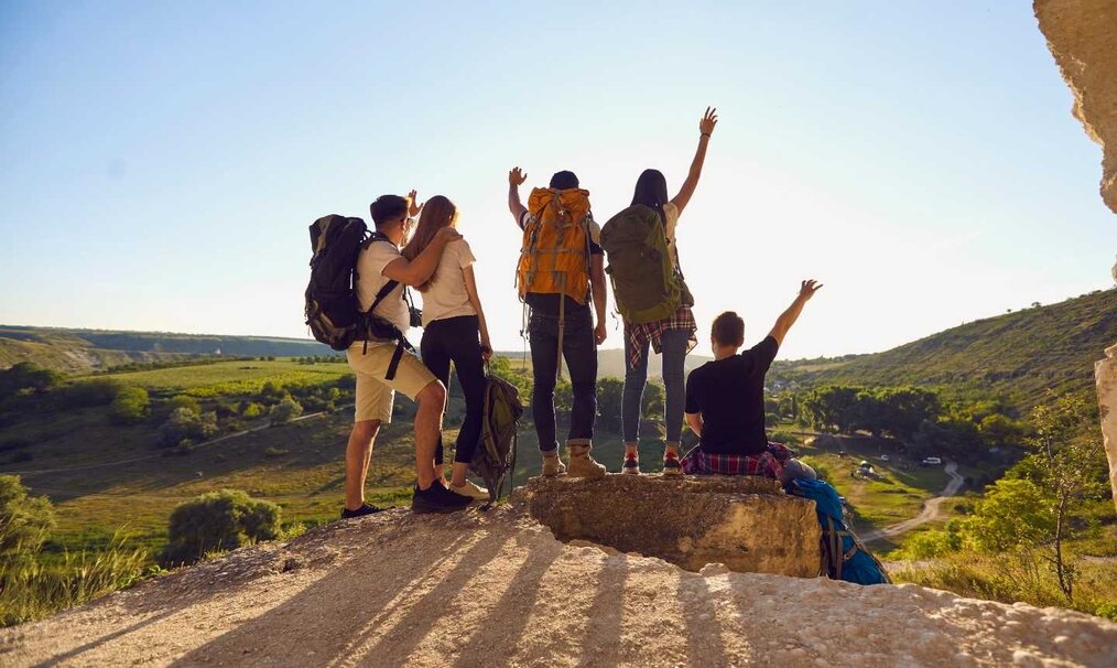 Group of travelers raising arms celebrating on a hill